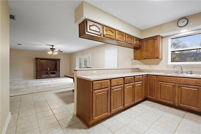 kitchen with sink, kitchen peninsula, ceiling fan, and light tile patterned flooring