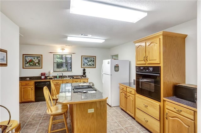 kitchen featuring a breakfast bar, sink, a center island, light tile patterned floors, and black appliances