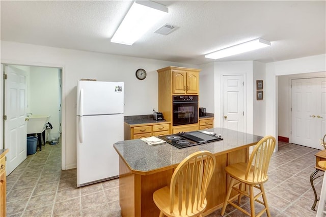 kitchen featuring a breakfast bar, a center island, light tile patterned floors, black appliances, and a textured ceiling