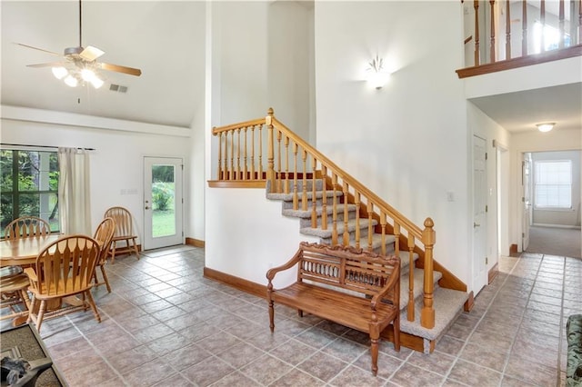 stairs with ceiling fan and high vaulted ceiling