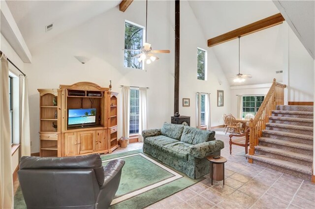 tiled living room with beamed ceiling, ceiling fan, and a wood stove