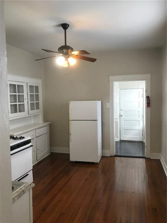 kitchen with dark wood-type flooring, white appliances, ceiling fan, and white cabinets