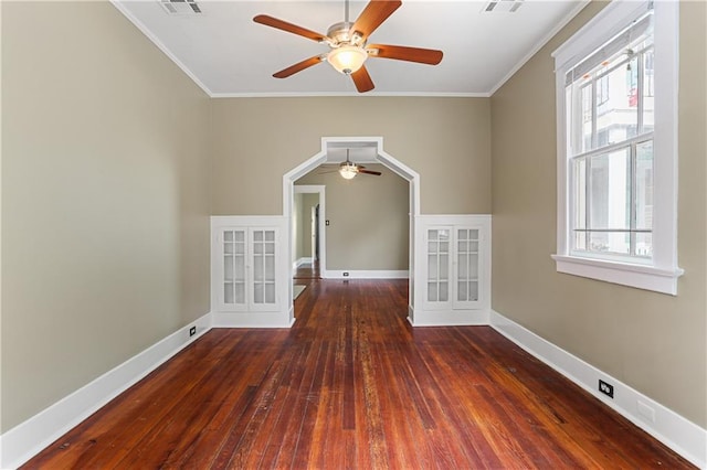 empty room featuring crown molding, dark hardwood / wood-style flooring, and a wealth of natural light