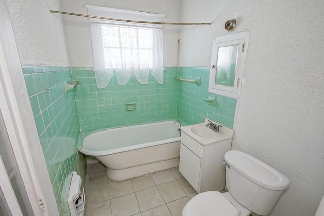 bathroom featuring a washtub, vanity, tile patterned flooring, and tile walls