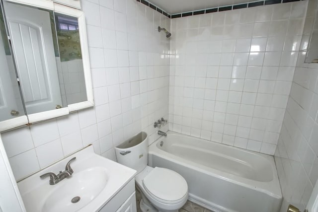 full bathroom featuring tiled shower / bath, tile walls, vanity, and toilet