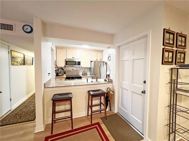 kitchen featuring wood-type flooring, a breakfast bar area, white cabinets, kitchen peninsula, and stainless steel appliances