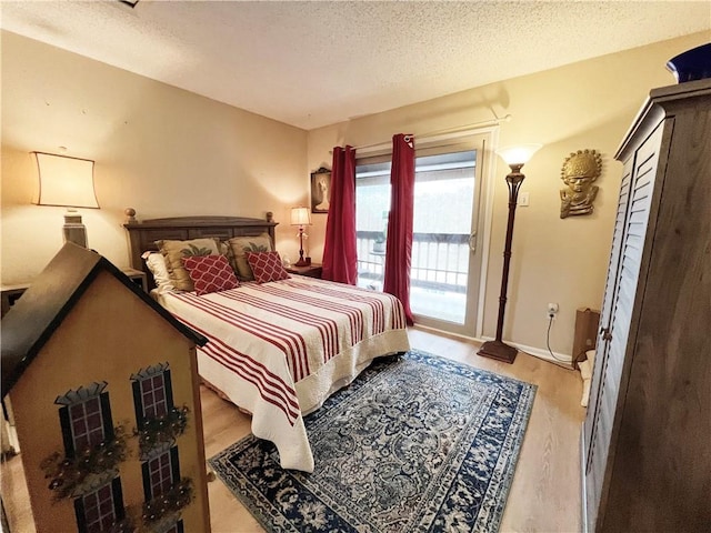 bedroom featuring a textured ceiling, access to exterior, and light wood-type flooring