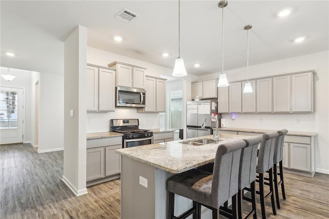 kitchen featuring pendant lighting, sink, a breakfast bar, stainless steel appliances, and an island with sink