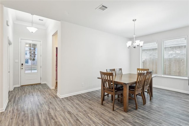 dining space with dark hardwood / wood-style flooring, ornamental molding, and a chandelier