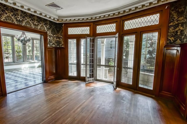 doorway with hardwood / wood-style flooring, ornamental molding, and a notable chandelier