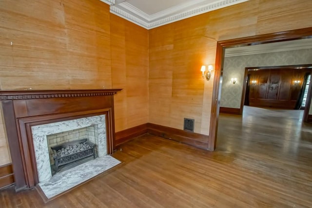 unfurnished living room featuring a high end fireplace, ornamental molding, and wood-type flooring