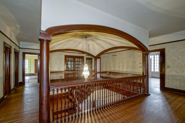 corridor with an inviting chandelier, wood-type flooring, and decorative columns