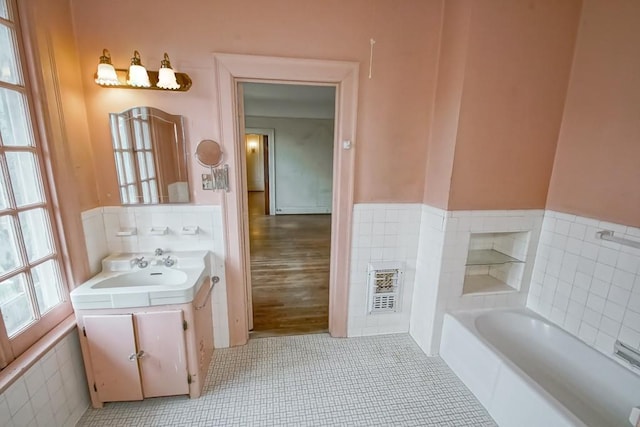 bathroom featuring tile walls, vanity, tile patterned flooring, and a bathing tub