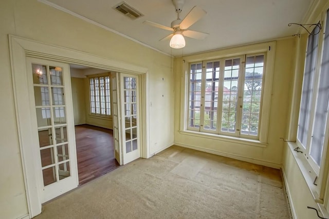 interior space featuring crown molding, light carpet, ceiling fan, and french doors