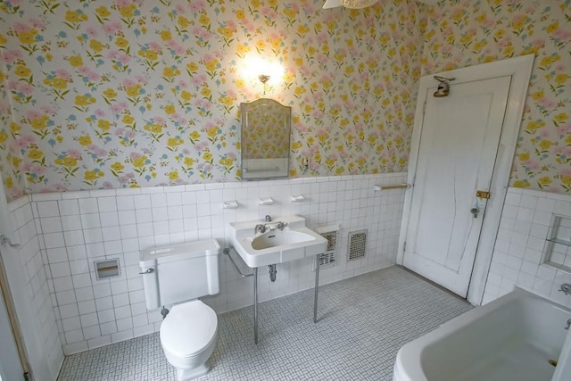 bathroom featuring a tub, sink, tile walls, tile patterned flooring, and toilet