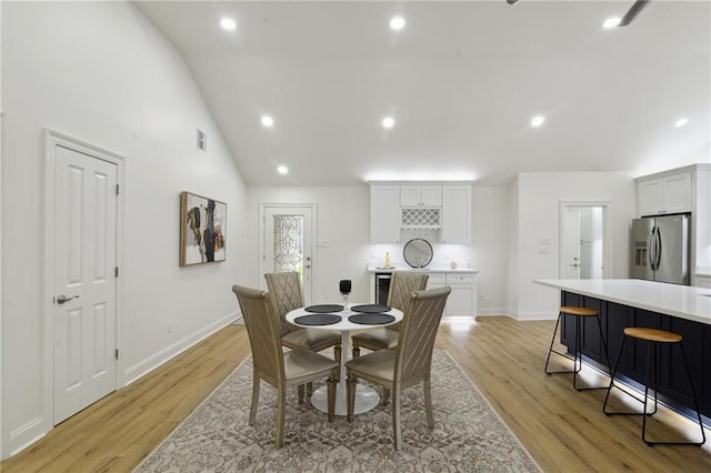 dining area with high vaulted ceiling and light wood-type flooring