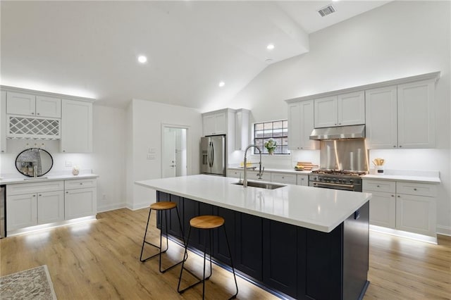 kitchen featuring appliances with stainless steel finishes, sink, a kitchen island with sink, and light hardwood / wood-style floors