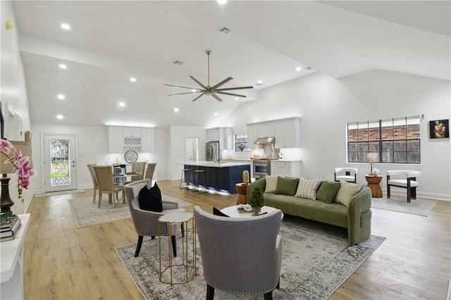 living room featuring ceiling fan, sink, high vaulted ceiling, and light hardwood / wood-style flooring