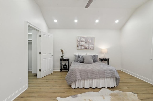 bedroom featuring ceiling fan, lofted ceiling, a walk in closet, and light wood-type flooring