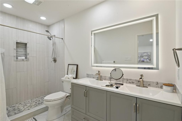 bathroom featuring vanity, toilet, and tiled shower