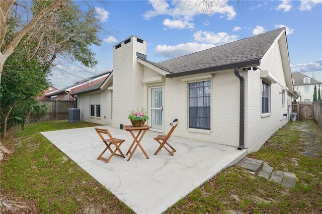 rear view of property with cooling unit, a patio area, and a lawn