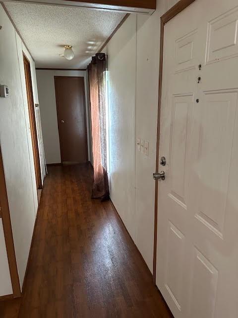 hallway featuring dark hardwood / wood-style floors and a textured ceiling