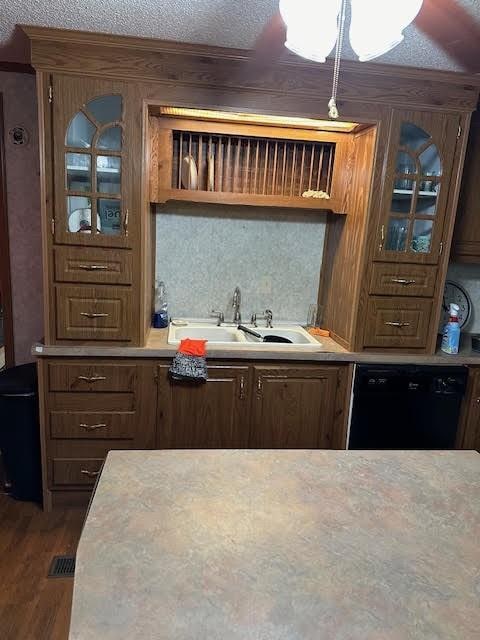 kitchen featuring sink, black dishwasher, a textured ceiling, and dark wood-type flooring