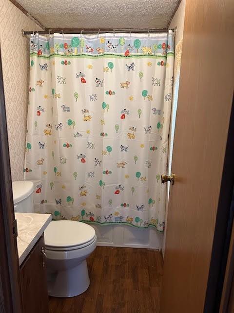 full bathroom with shower / bath combo with shower curtain, wood-type flooring, vanity, and a textured ceiling