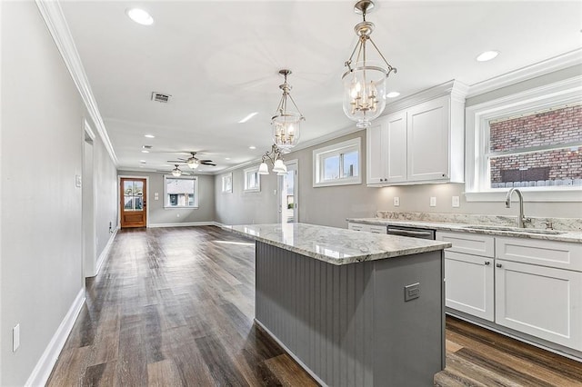 kitchen with sink, white cabinetry, light stone counters, a kitchen island, and decorative light fixtures