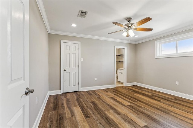 unfurnished bedroom featuring crown molding, dark hardwood / wood-style floors, ceiling fan, and ensuite bath