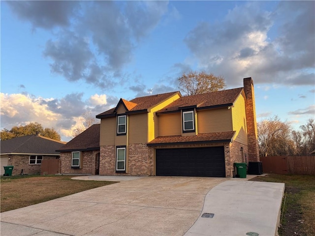 front of property with a garage, a yard, and central AC