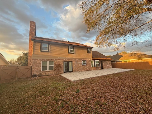 back house at dusk with a lawn and a patio area