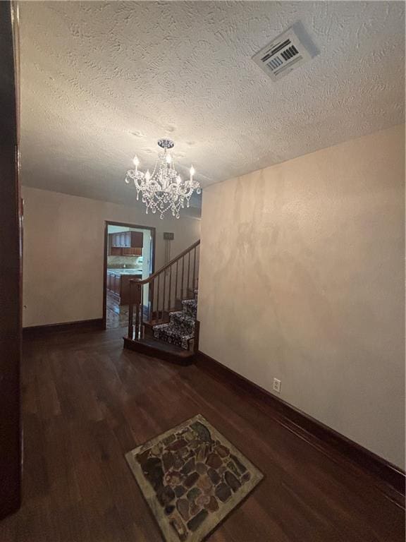 interior space with dark wood-type flooring, an inviting chandelier, and a textured ceiling