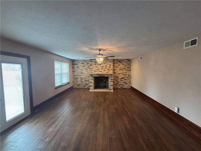 unfurnished living room with ceiling fan, dark hardwood / wood-style floors, a textured ceiling, and a fireplace