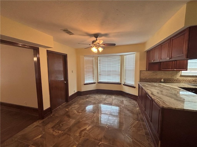 kitchen with ceiling fan, light stone countertops, decorative backsplash, and a textured ceiling