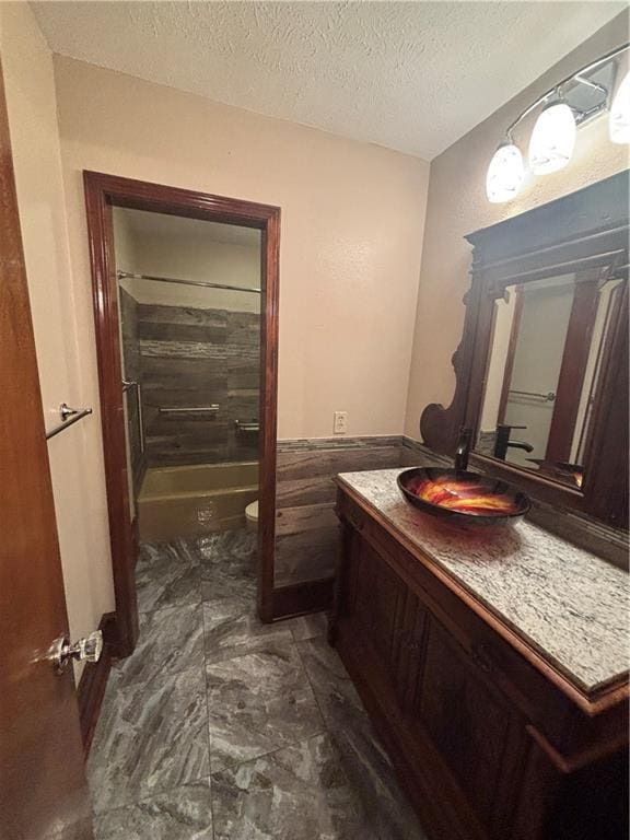 full bathroom with shower / bathtub combination, vanity, toilet, and a textured ceiling