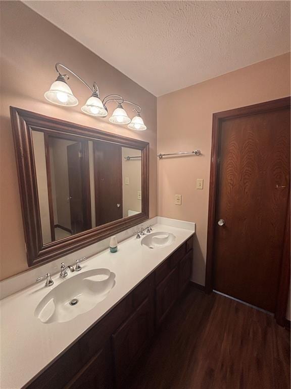 bathroom with hardwood / wood-style flooring, vanity, and a textured ceiling