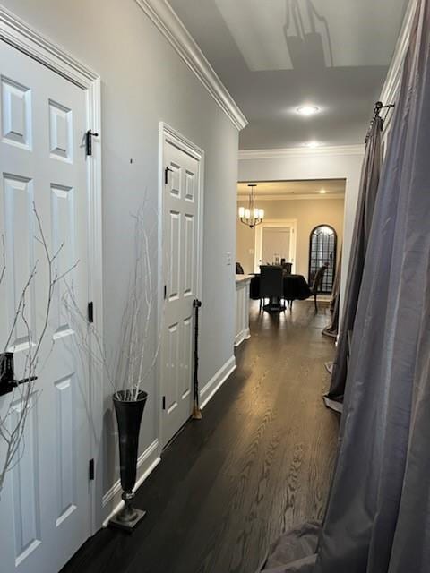 hall featuring dark wood-type flooring, ornamental molding, and an inviting chandelier