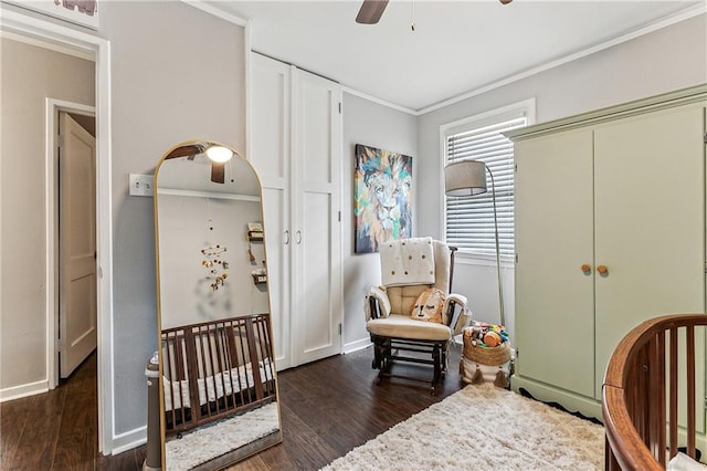 bedroom with dark wood-type flooring, ornamental molding, a nursery area, and ceiling fan