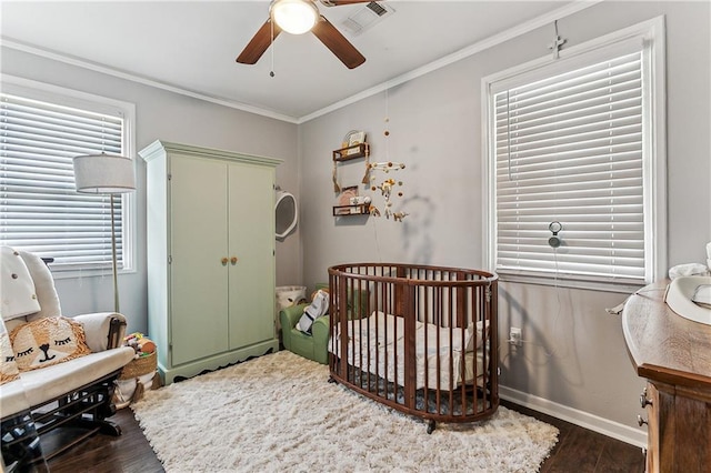 bedroom with ornamental molding, dark hardwood / wood-style floors, a closet, ceiling fan, and a crib