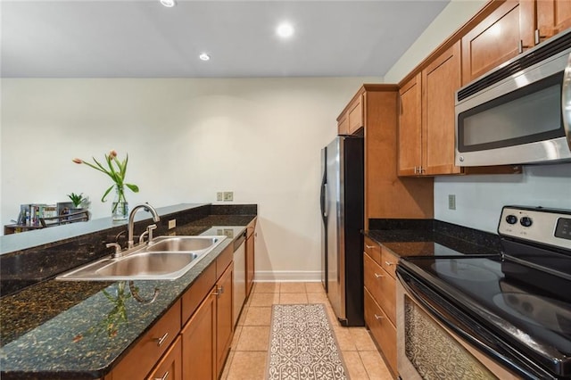 kitchen with sink, light tile patterned floors, stainless steel appliances, and dark stone counters