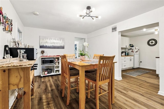 dining area featuring hardwood / wood-style flooring and an inviting chandelier