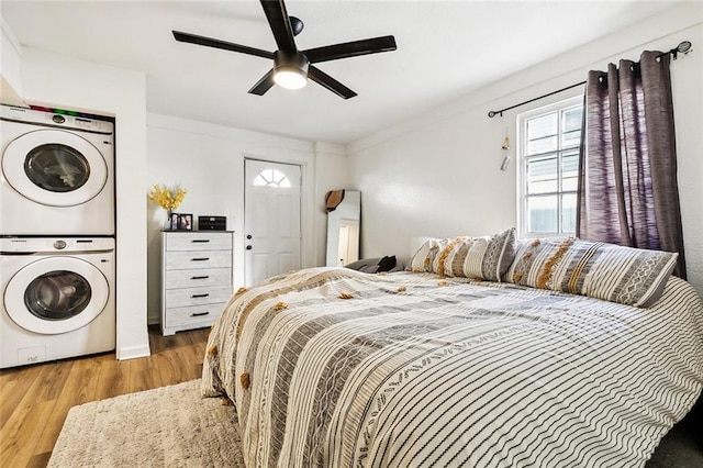 bedroom with stacked washer and dryer, ceiling fan, and light hardwood / wood-style flooring