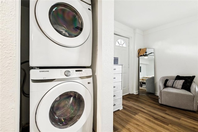 washroom with dark wood-type flooring and stacked washing maching and dryer