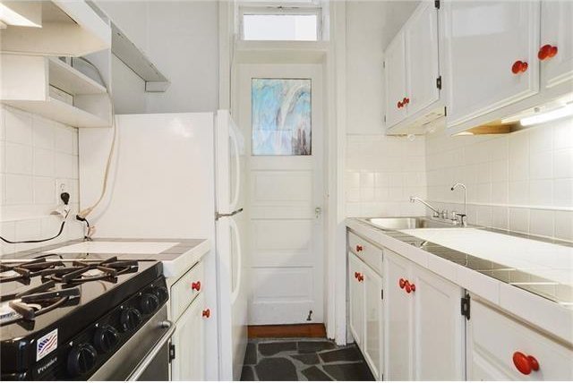 kitchen with gas range, tile counters, decorative backsplash, and white cabinets