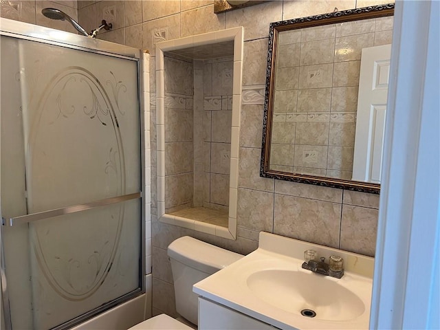 full bathroom with enclosed tub / shower combo, vanity, tile walls, and toilet