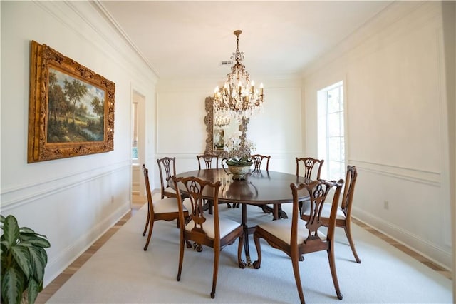 dining space featuring an inviting chandelier, ornamental molding, and light wood-type flooring