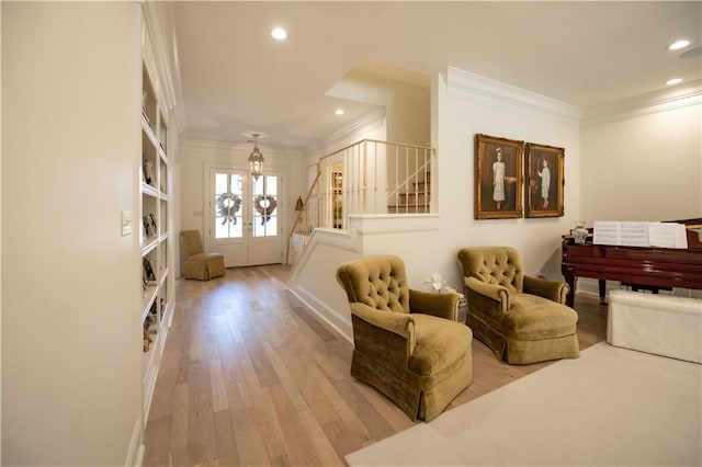 living area with ornamental molding, light hardwood / wood-style floors, and french doors