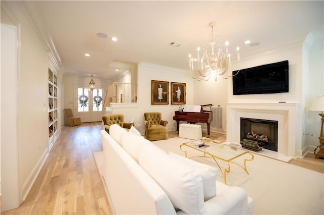 living room with french doors, crown molding, an inviting chandelier, and light hardwood / wood-style flooring