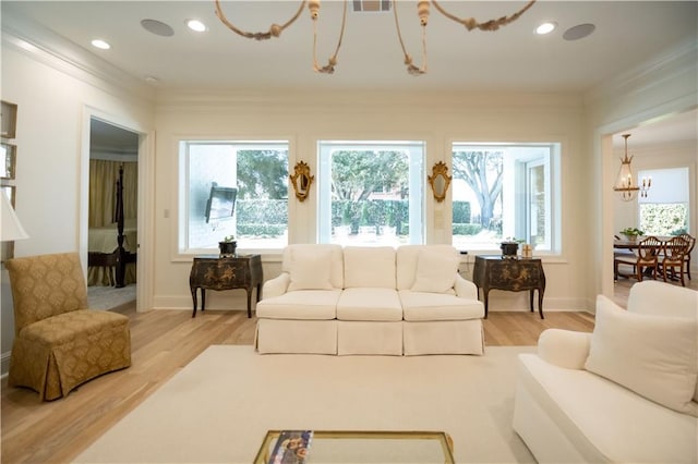 living room with ornamental molding, light hardwood / wood-style floors, and a notable chandelier